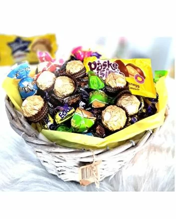 På bildet ser vi en elegant flettet kurv med assorterte, innpakkede sjokolader og Ferrero Rocher øverst.