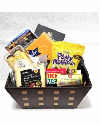 Bildet viser en elegant, sort pappeske fylt med ulike påskegodbiter som Ferrero Rocher, manchego, Kvikklunsj og melkesjokolade, pent pakket i cellofan og klar for levering over hele Norge.